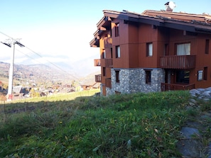 A multi-story wooden building with balconies, set against a mountainous backdrop. - Apartment with pets allowed - Ski-in access (Valmorel)