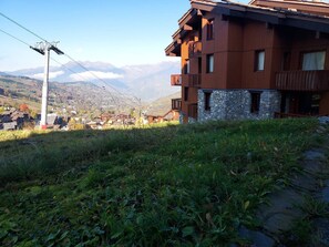 A multi-story wooden building with balconies, set against a mountainous backdrop. - Apartment with pets allowed - Ski-in access (Valmorel)