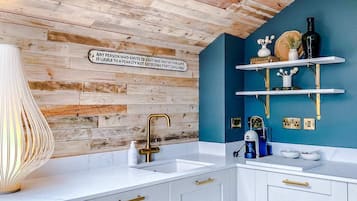 A kitchen with a wooden ceiling, white cabinets, and a blue accent wall.