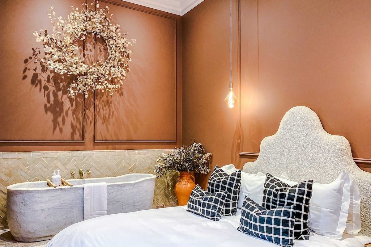 A bedroom with a large bed, a bathtub, and a decorative wall piece.