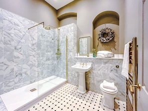 A bathroom with a glass-enclosed shower, a pedestal sink, and a toilet.