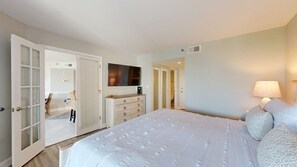 Une chambre à coucher avec un lit, une commode, un téléviseur et une lampe.