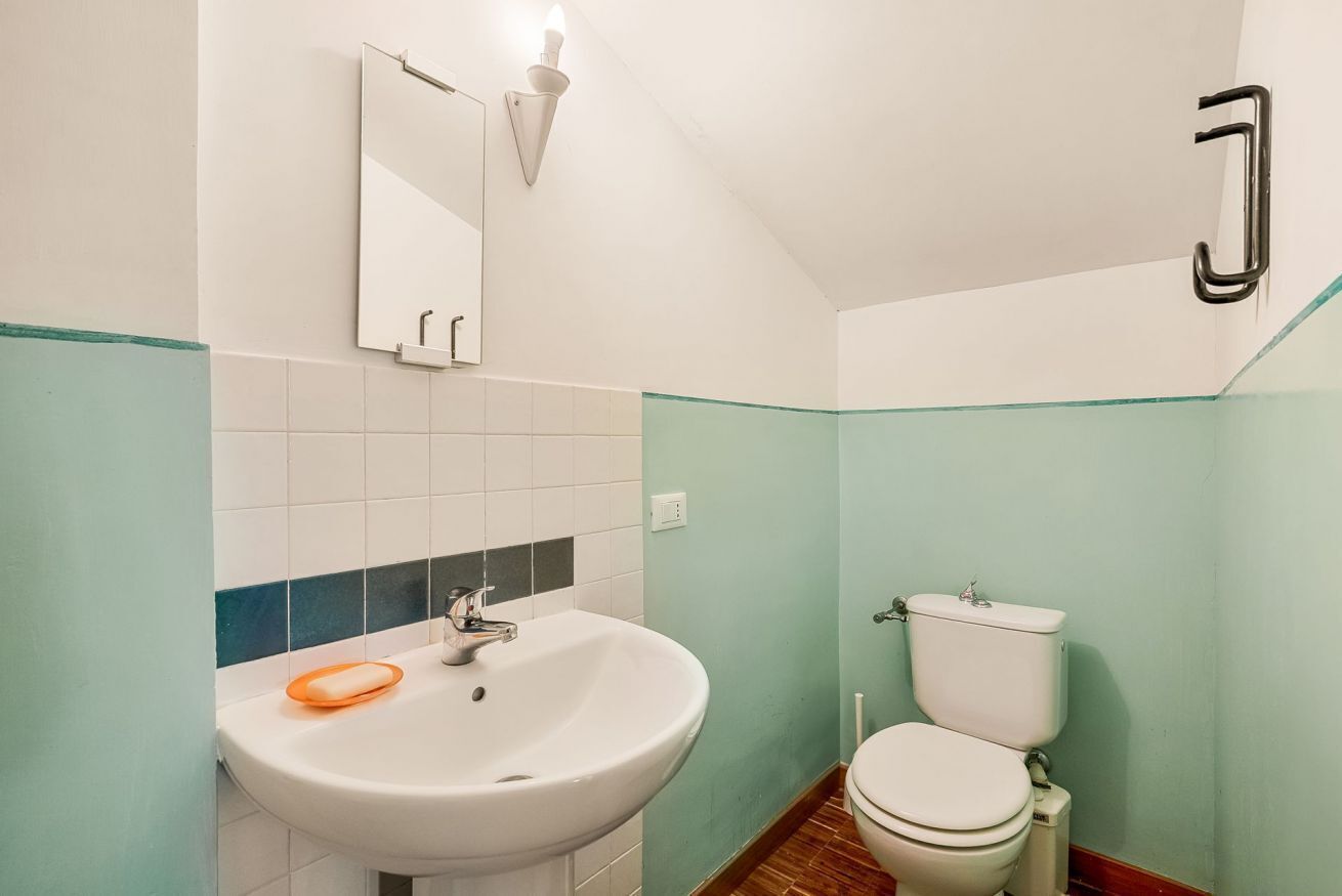 A bathroom with a white sink, a toilet, and a mirror.
