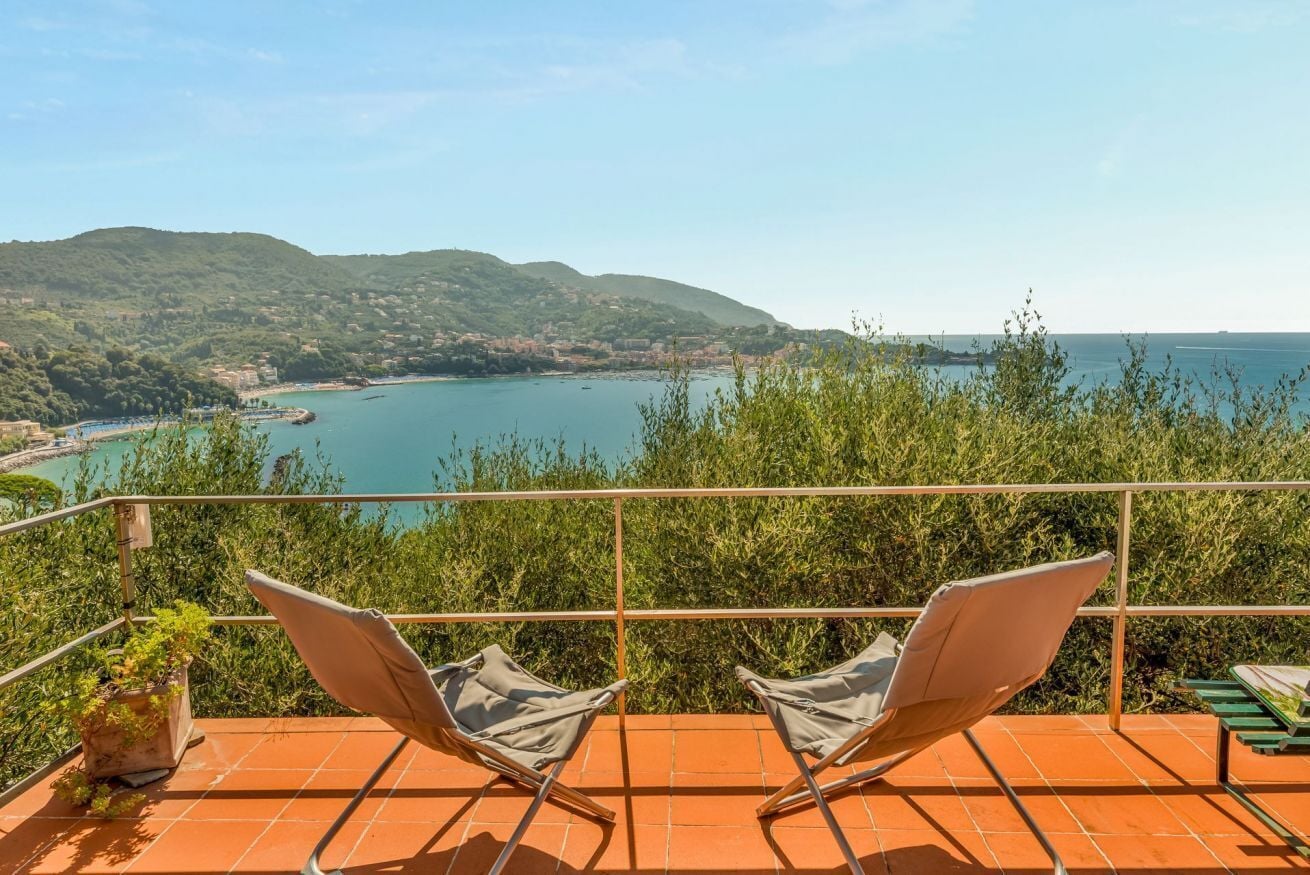 A terrace with two lounge chairs overlooking a coastal view.