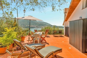 Eine Terrasse im Freien mit Tisch, Stühlen und Sonnenschirm.