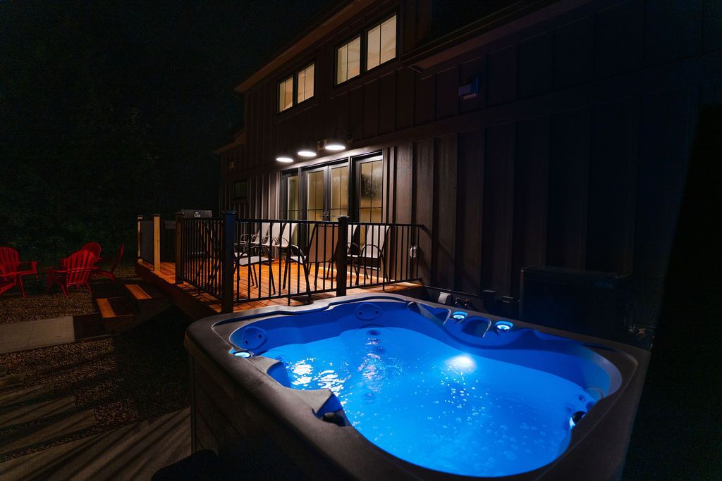 Ein Whirlpool vor einem Haus mit einer Terrasse und roten Stühlen.