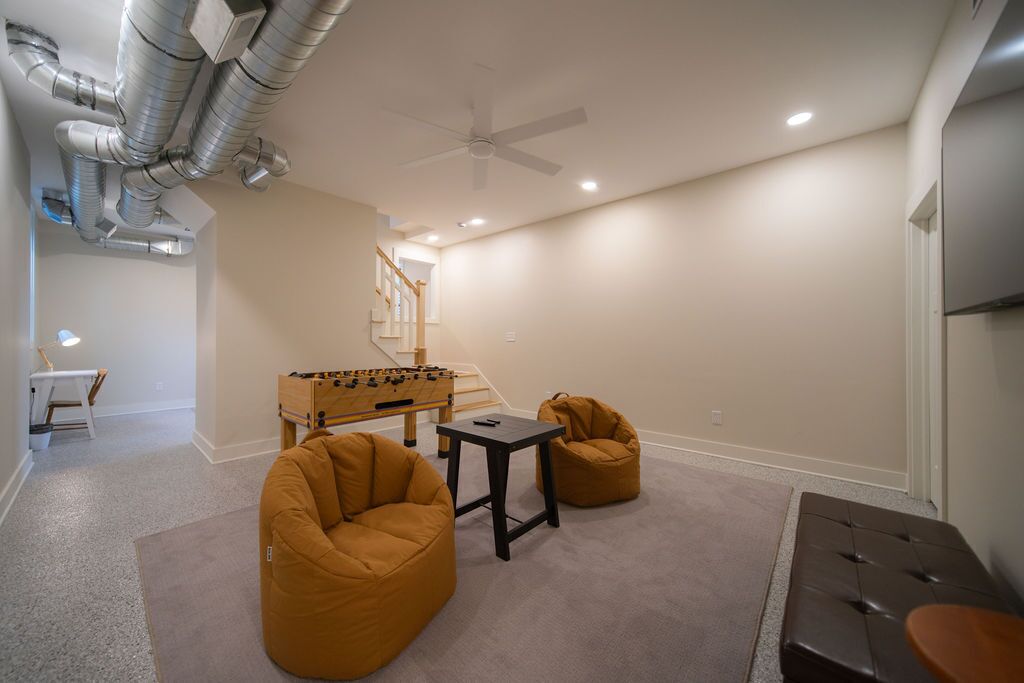 A room with a foosball table, two bean bags, a small table, and a ceiling fan.