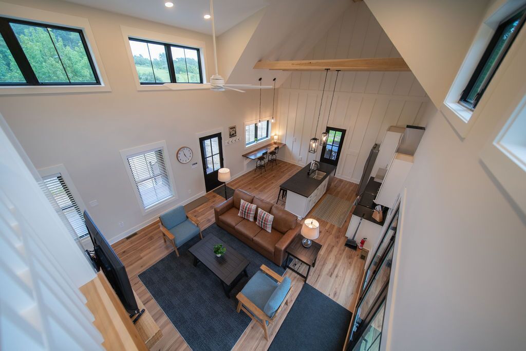 A spacious living area with a high ceiling, wooden flooring, and a cozy seating arrangement.