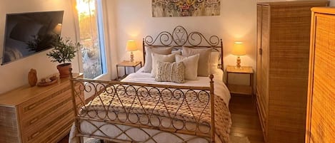 Quarto com cama, mesas de cabeceira, cômoda, janela e um quadro na parede.
