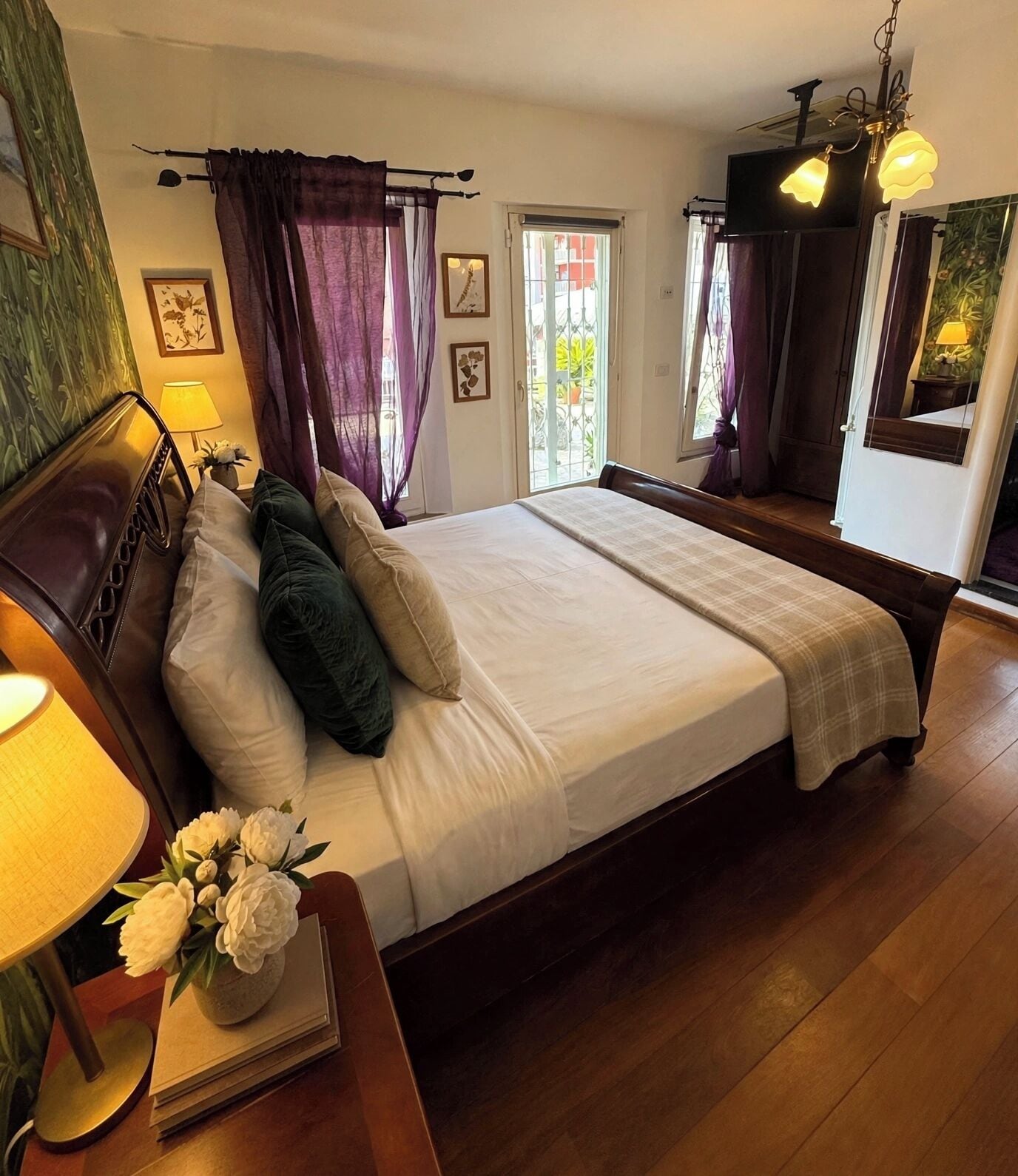 Een slaapkamer met een groot bed, een nachtkastje met lamp, een dressoir en een spiegel.