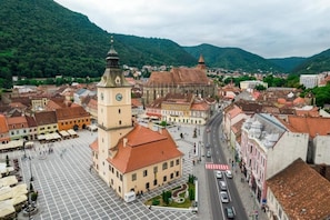 Ein Stadtplatz mit einem markanten Glockenturm, umgeben von historischen Gebäuden und einer Bergkulisse.