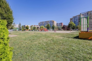 Un parque con juegos infantiles, una bicicleta y edificios residenciales al fondo.