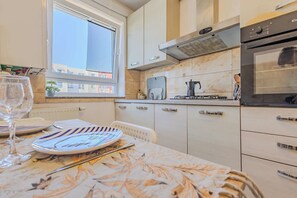 Eine moderne Küche mit Fenster, einem Herd und einem Esstisch, gedeckt mit Tellern und einem Glas.
