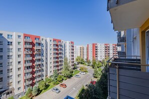 Zona residencial con edificios de apartamentos de varios pisos, cielo despejado y una calle con coches estacionados.