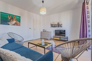A modern living room with a sofa, chairs, a TV, and artwork on the walls. - Bright 2BR Apt · Free Parking · 10 min to Old Town (Brașov)