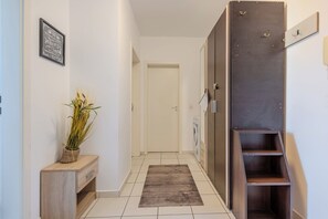 A hallway with a wooden bench, a potted plant, a door, and a staircase. - Bright 2BR Apt · Free Parking · 10 min to Old Town (Brașov)