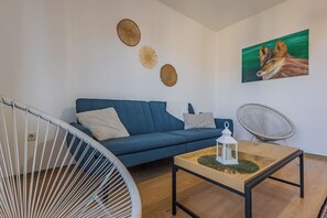 A modern living room with a blue sofa, a white chair, a round table with a candle, and a painting of a fox on the wall. - Bright 2BR Apt · Free Parking · 10 min to Old Town (Brașov)
