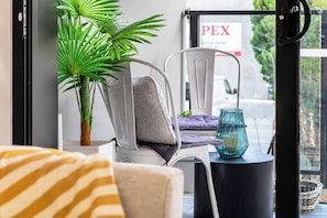 A balcony with a chair, a potted plant, a glass candle holder, and a sign reading 'PEX'. - Hawthorn 2BR Apartment | 2 Queen Beds | Balcony (Hawthorn)