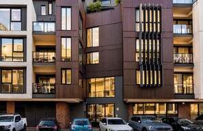A multi-story building with balconies, large windows, and a parking area with various cars. - Hawthorn 2BR Apartment | 2 Queen Beds | Balcony (Hawthorn)