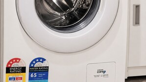 Uma máquina de lavar roupa Samsung digital inverter com porta transparente, painel de comandos com diversas opções de lavagem e etiqueta de classificação energética da água.