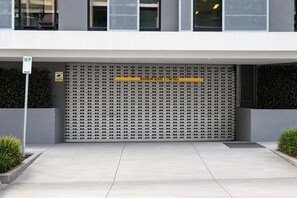 A building entrance with a metal garage door, a height restriction sign, and a sign indicating a maximum height of 2.1 meters. - Hawthorn 2b charming retreat (Hawthorn)