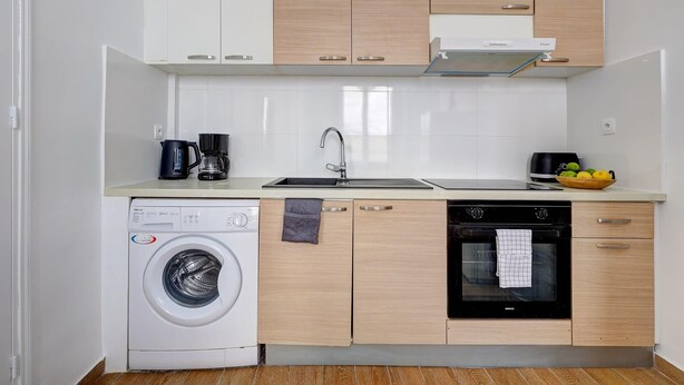 Una cocina compacta equipada con lavadora, lavavajillas, horno y cafetera.