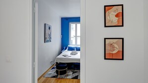 Un dormitorio con cama, ventana y dos cuadros en la pared.