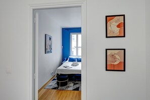 Ein Schlafzimmer mit einem Bett, einem Fenster und zwei gerahmten Kunstwerken an der Wand.