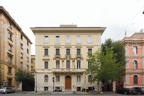 Ein Gebäude mit einem zentralen Eingang, mehreren Fenstern und einem Balkon.