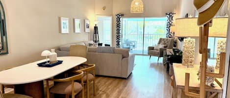 A modern living room with a dining area, large windows, and a view of the outdoors.