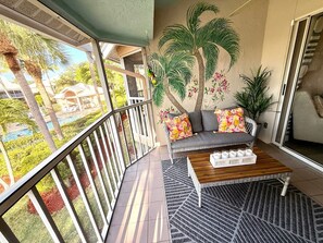 Ein Balkon mit einer Couch, einem Couchtisch und einem dekorativen Wandbild.