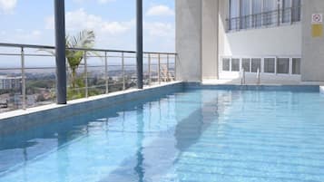 An indoor swimming pool with a view of the cityscape.