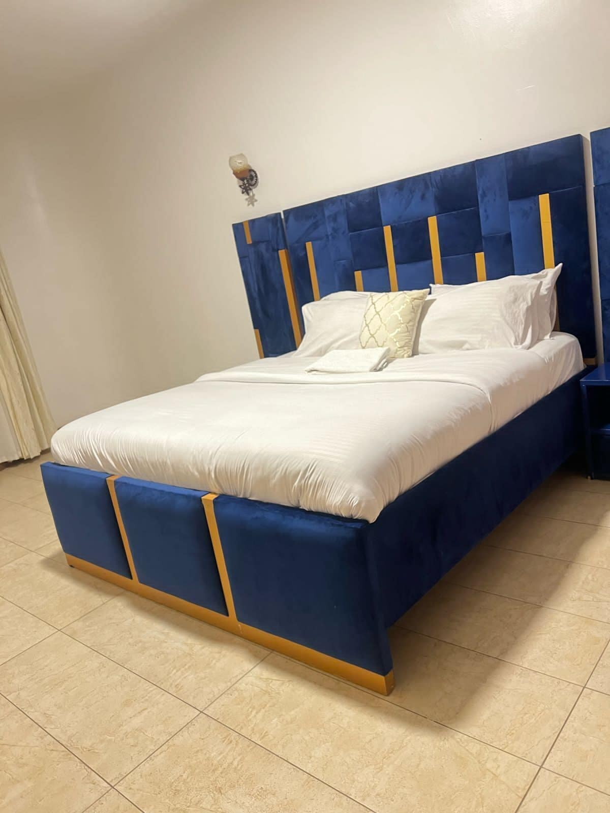 A bed with a blue headboard and footboard, white bedding, and a small bedside table.