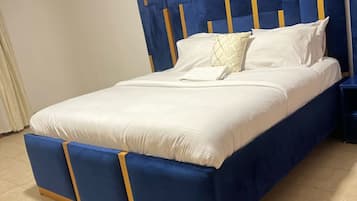 A bed with a blue headboard and footboard, white bedding, and a small bedside table.