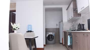 A compact kitchen with a washing machine, a dining area with a chair, and a small table.