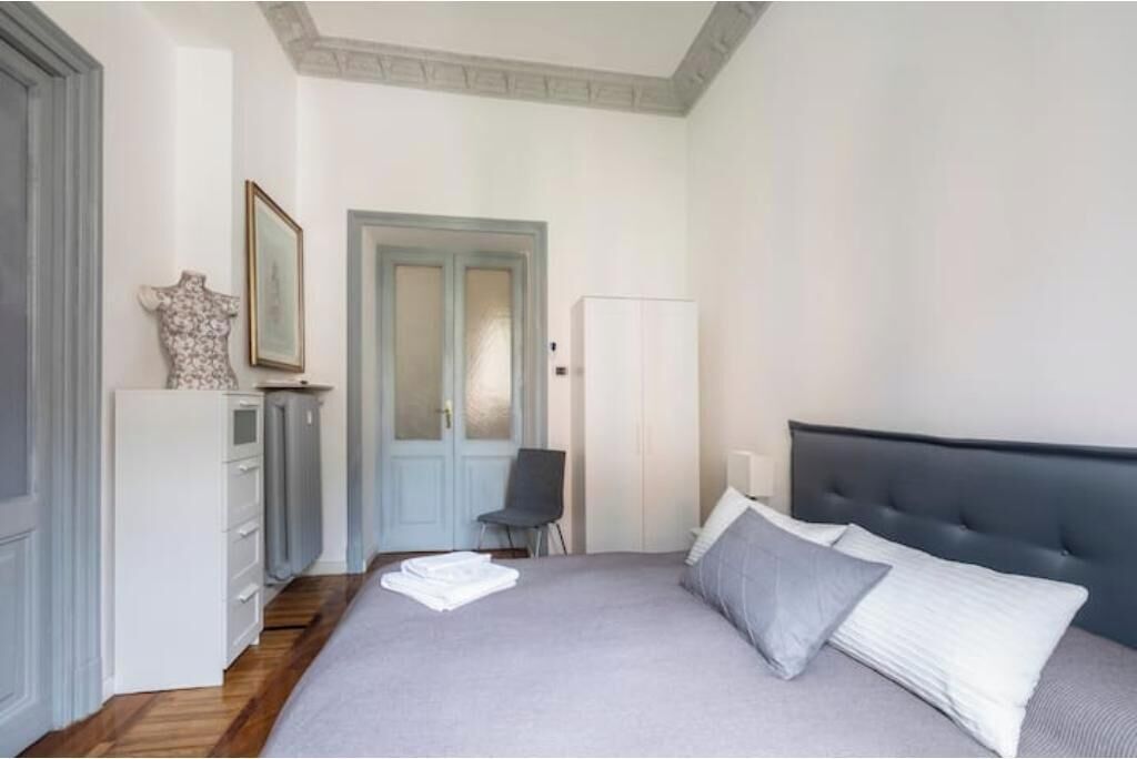 Een slaapkamer met een bed, een stoel, een kledingkast en een deur.