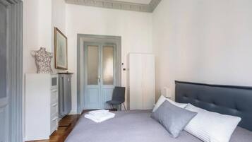 Een slaapkamer met een bed, een stoel, een kledingkast en een deur.