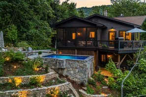 Ein zweistöckiges Haus mit einem Steinschwimmbecken, umgeben von üppiger Vegetation.