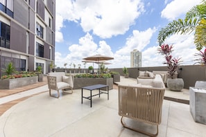 Terraza en la azotea con mobiliario exterior, una mesa y plantas en macetas.