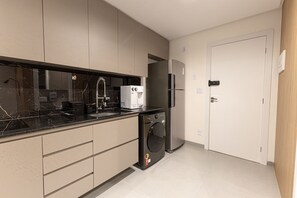 Una cocina moderna con lavavajillas integrado, refrigerador y pileta con grifo.