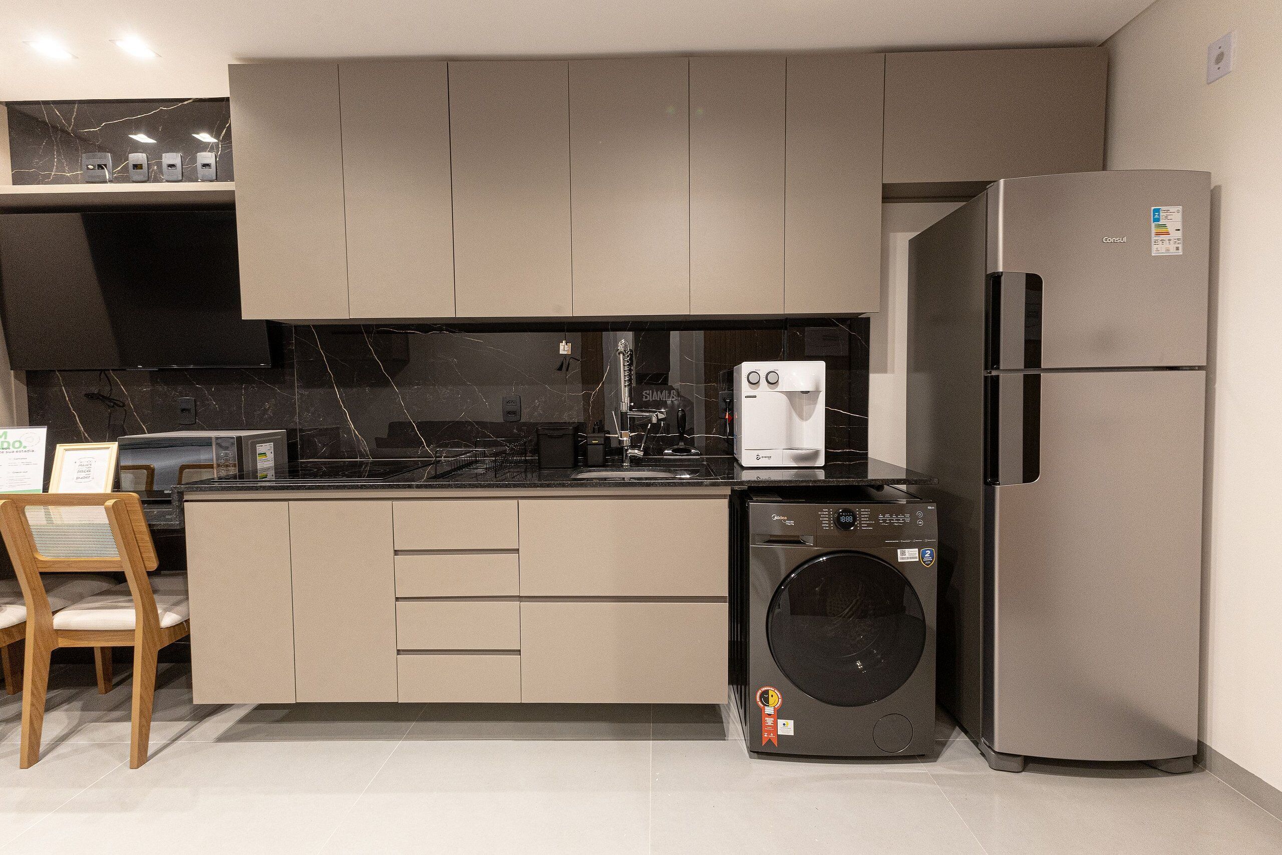 A modern kitchen with a built-in washing machine, a refrigerator, and a coffee machine.