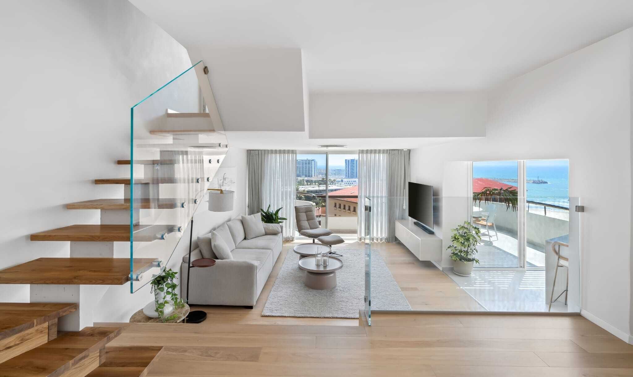 Un intérieur moderne avec un escalier, un salon et un balcon offrant une vue dégagée.