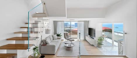A modern interior with a staircase, living room, and balcony with a view.