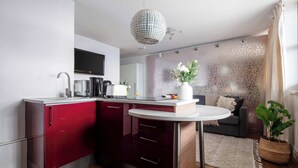 A modern kitchen with a red and white color scheme, a round dining table, and a decorative plant. - 1BR by Piccadilly Circus & Trafalgar Square (London)