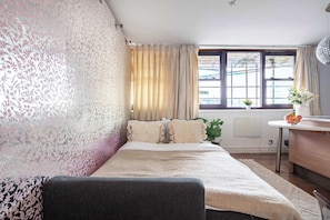 Een slaapkamer met een bed, een bureau en een raam met gordijnen.