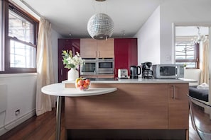 A modern kitchen with wooden cabinets, a white countertop, and stainless steel appliances. - 1BR by Piccadilly Circus & Trafalgar Square (London)