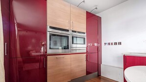 A modern kitchen with two ovens, wooden cabinets, and a white countertop. - 1BR by Piccadilly Circus & Trafalgar Square (London)