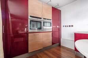 A modern kitchen with two ovens, wooden cabinets, and a white countertop. - 1BR by Piccadilly Circus & Trafalgar Square (London)