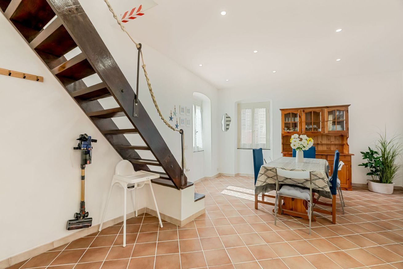 Une pièce spacieuse avec un escalier, un coin repas comprenant une table et des chaises, et un buffet en bois.