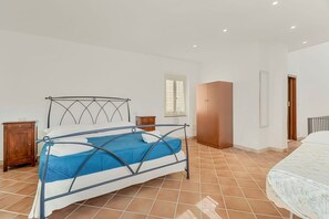 A bedroom with a metal bed frame, a blue bedspread, a wooden nightstand, and a wooden wardrobe. - [La Torretta] 5Terre-Golfo dei Poeti (La Spezia)